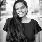 This is a black and white photo of Soumya Palreddy standing outside. Soumya has long black hair and is wearing a black dress. 