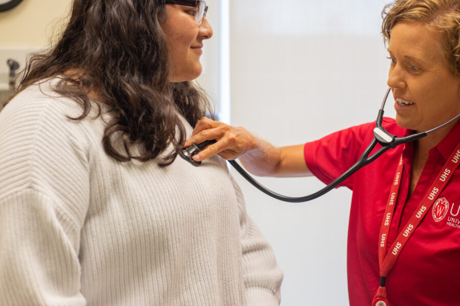 A UHS clinician places a stethoscope on a student's chest.