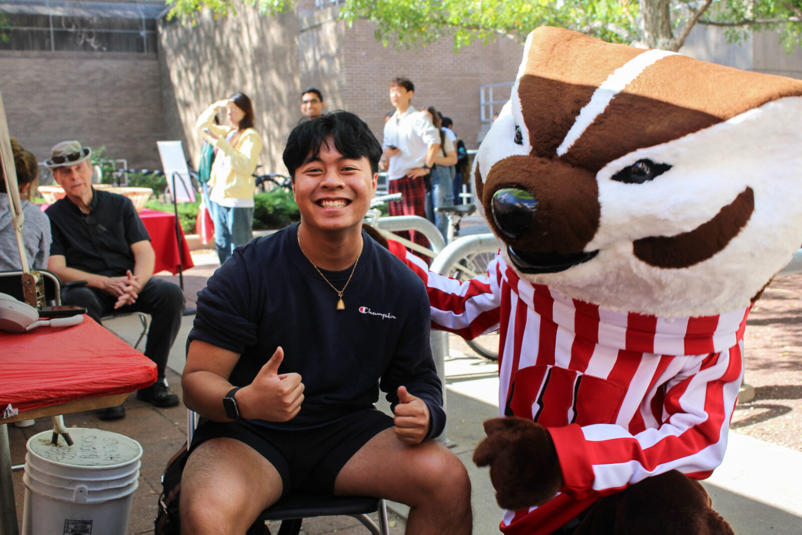 A student makes a thumbs up next to Bucky Badger at a UHS vaccine clinic