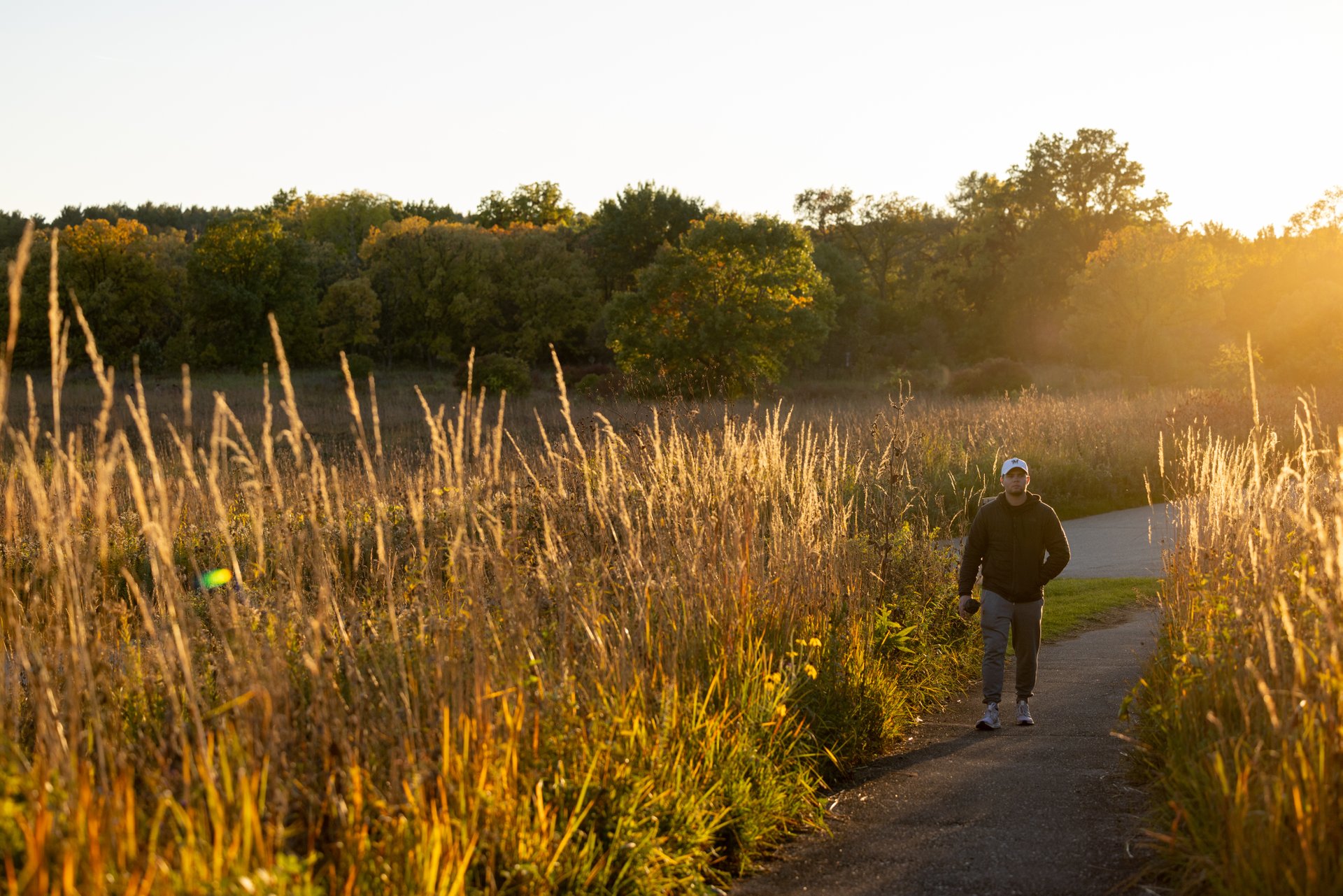 Person walking on a paved trail through the Arboretum.