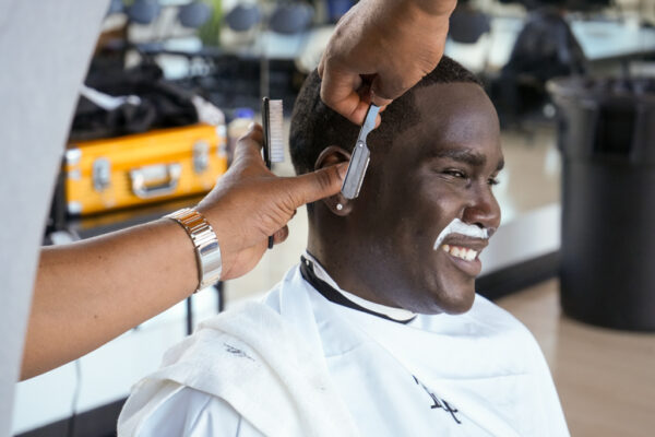 Student smiles as they receive a free haircut at barbershop talks in 2023.