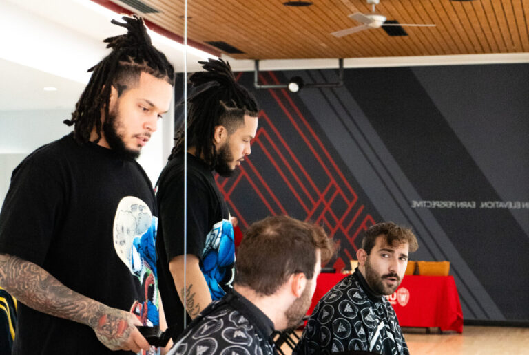 Barber cutting a students hair as they look in the mirror.