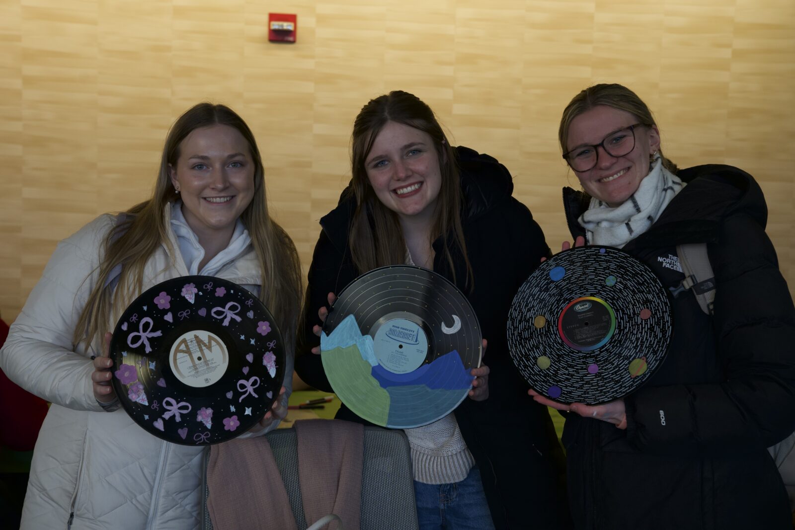 Three students posing with their painted vinyl records at Chillax in 2026.