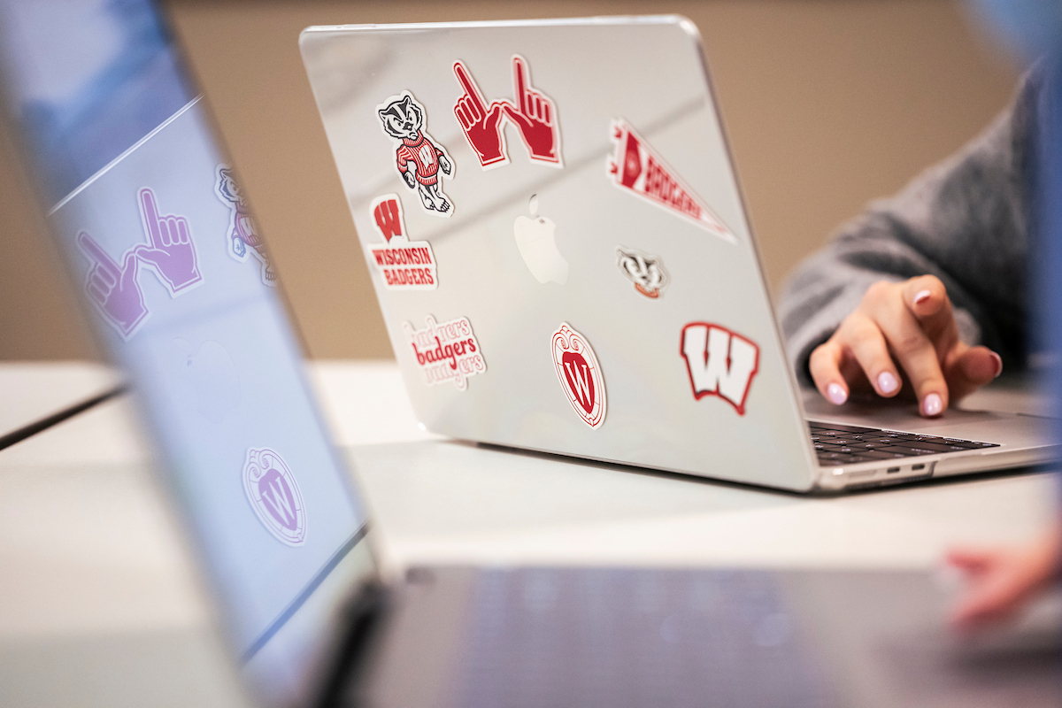 A student works on a laptop with UW stickers on the back