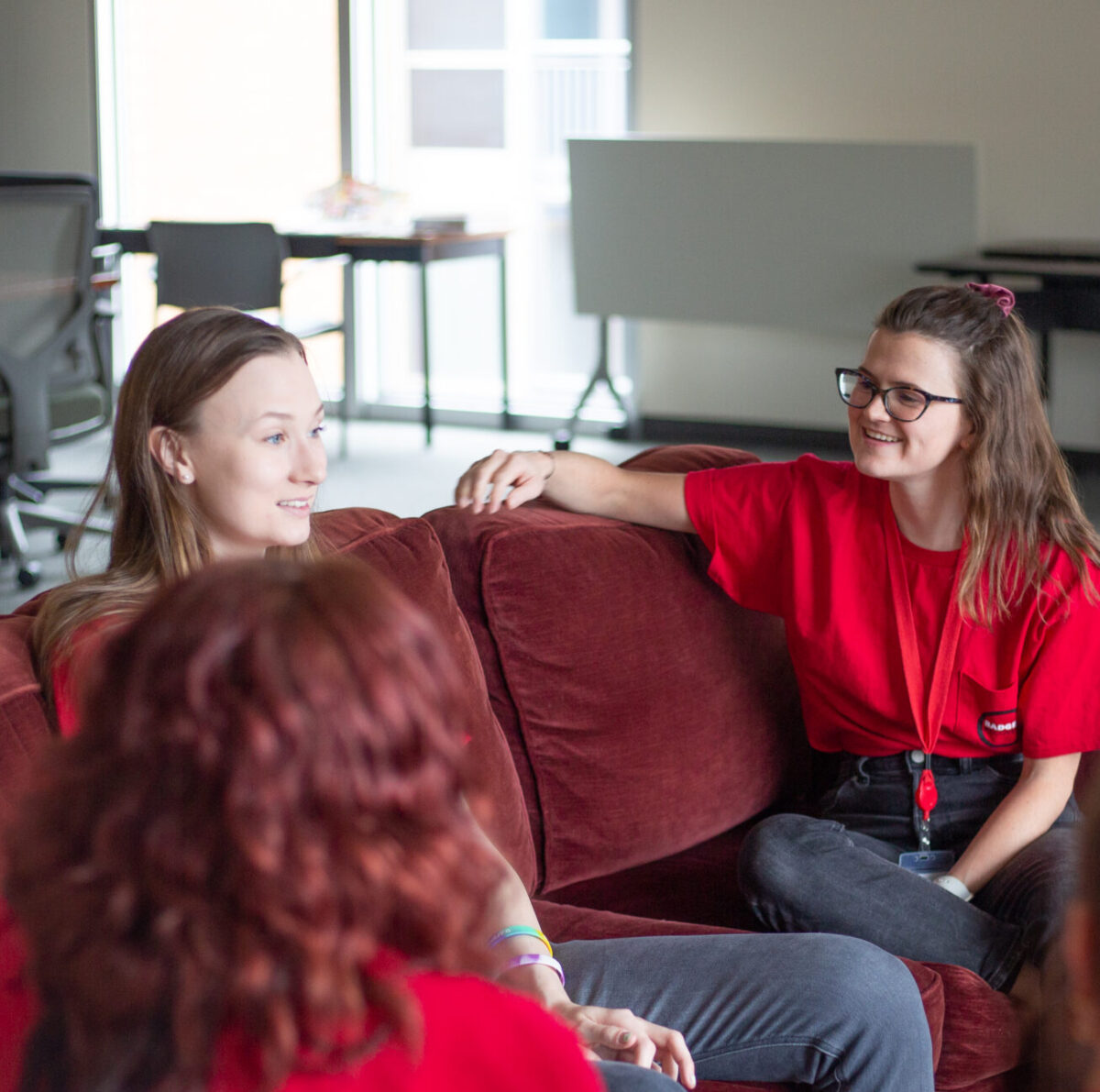Students of badger recovery seated on a red couch speaking to each other.