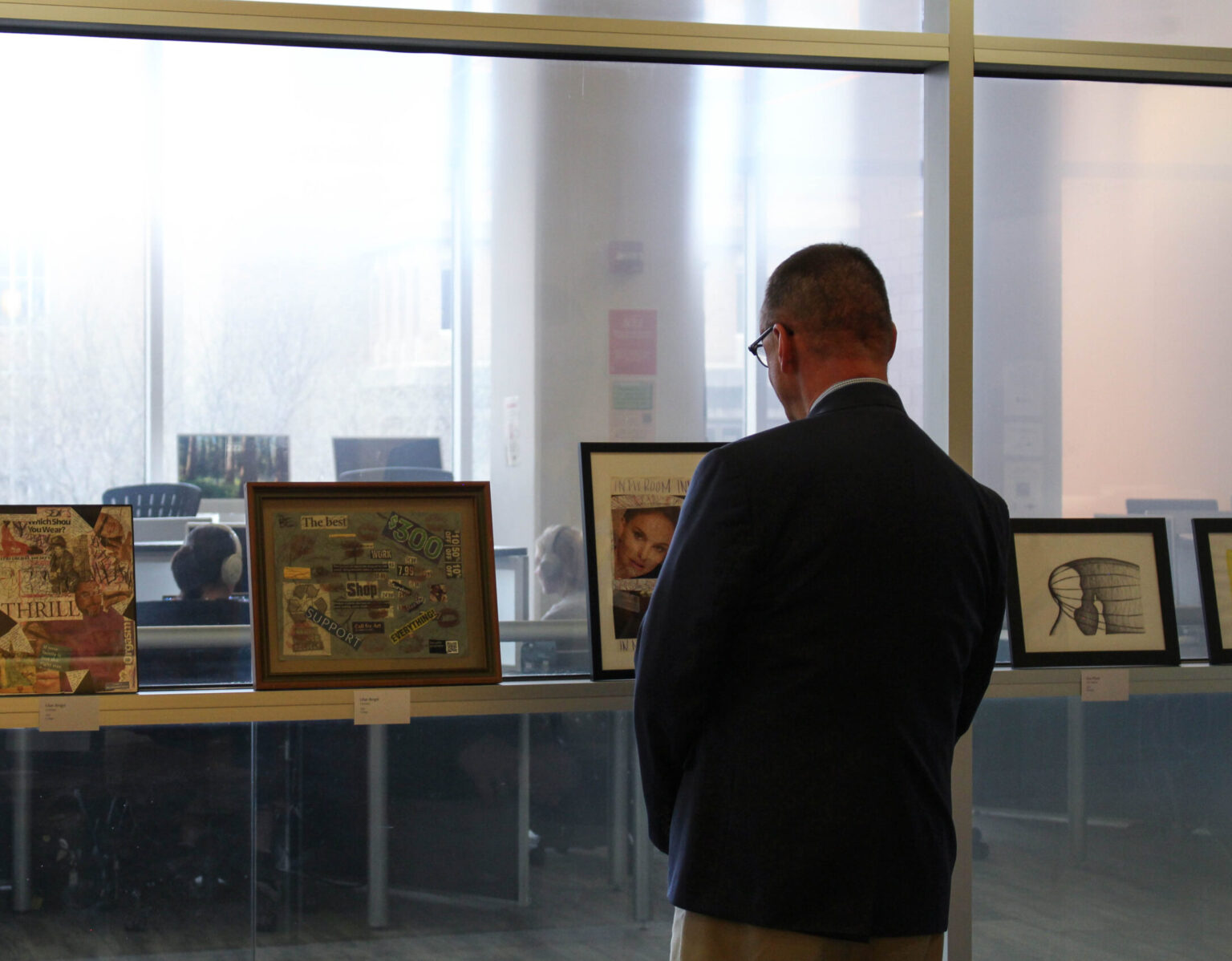 Person standing in front of art that is leaned against a window ledge.