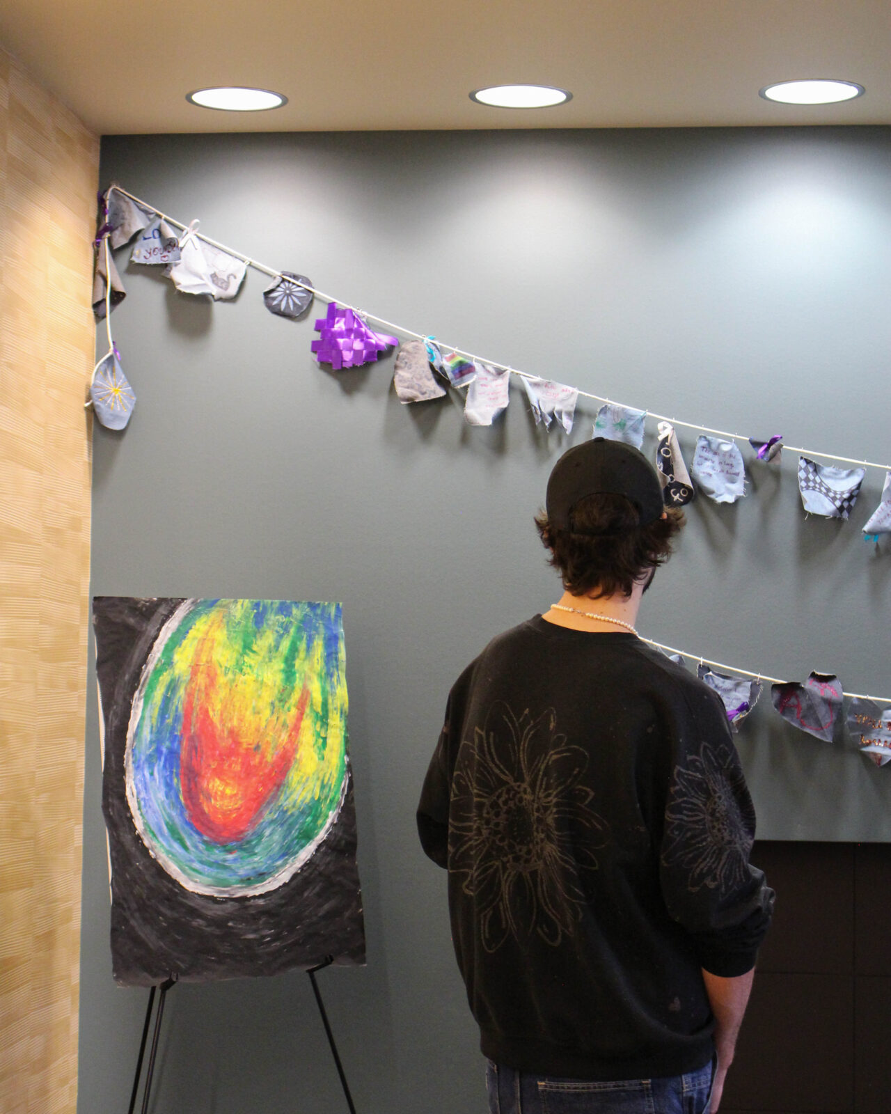Person views a denim banner and collaborative art piece at the survivor art gallery.