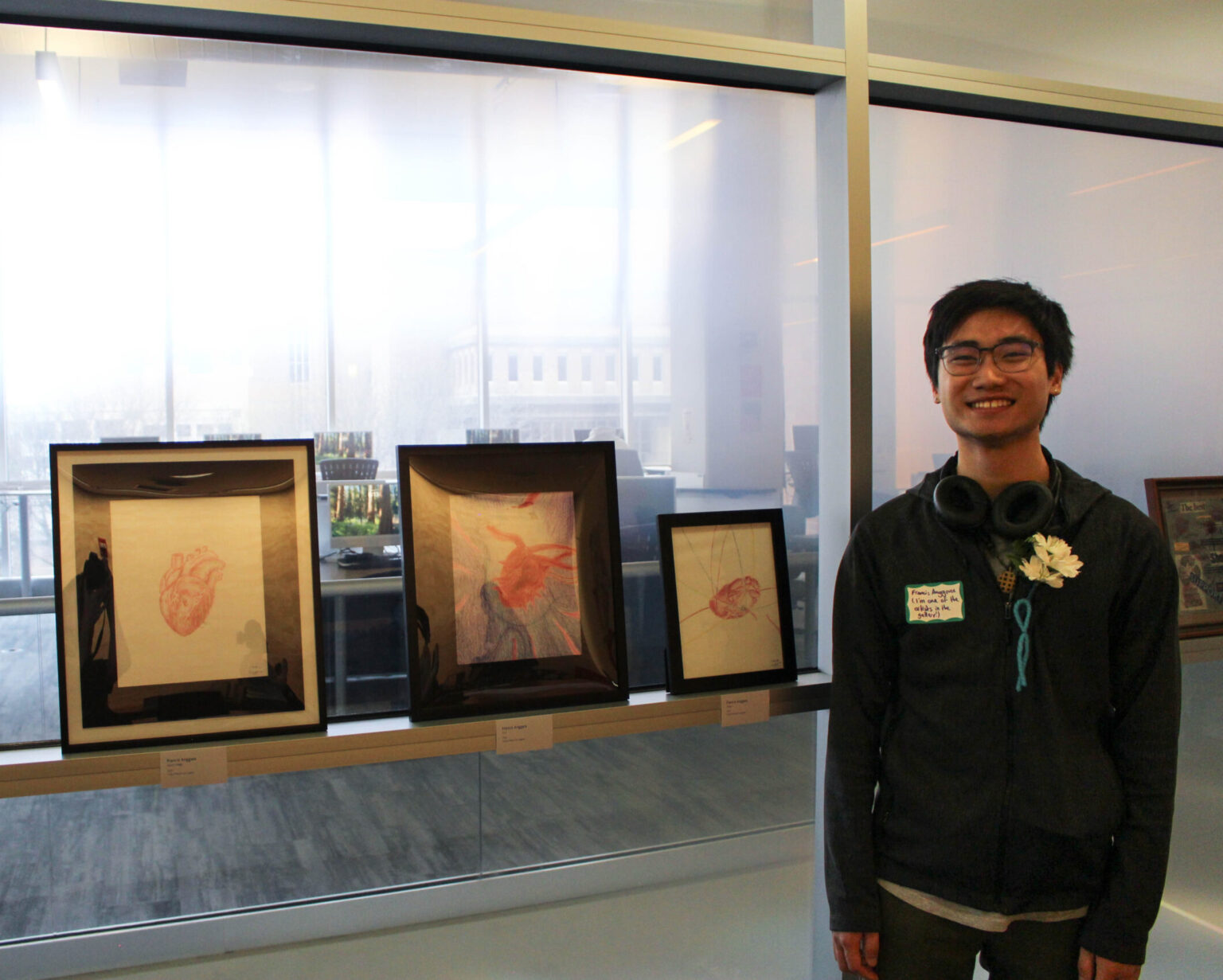 Student stands with their artwork featured in the survivor art gallery.
