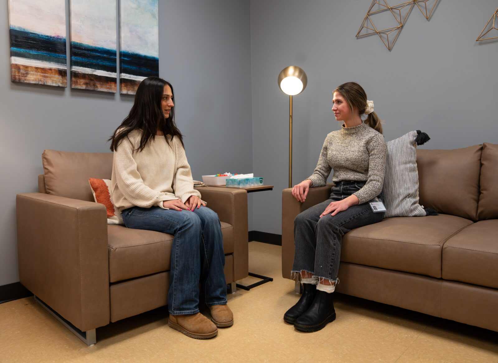 A student and Survivor Services advocate seated on a couch and chair talking.