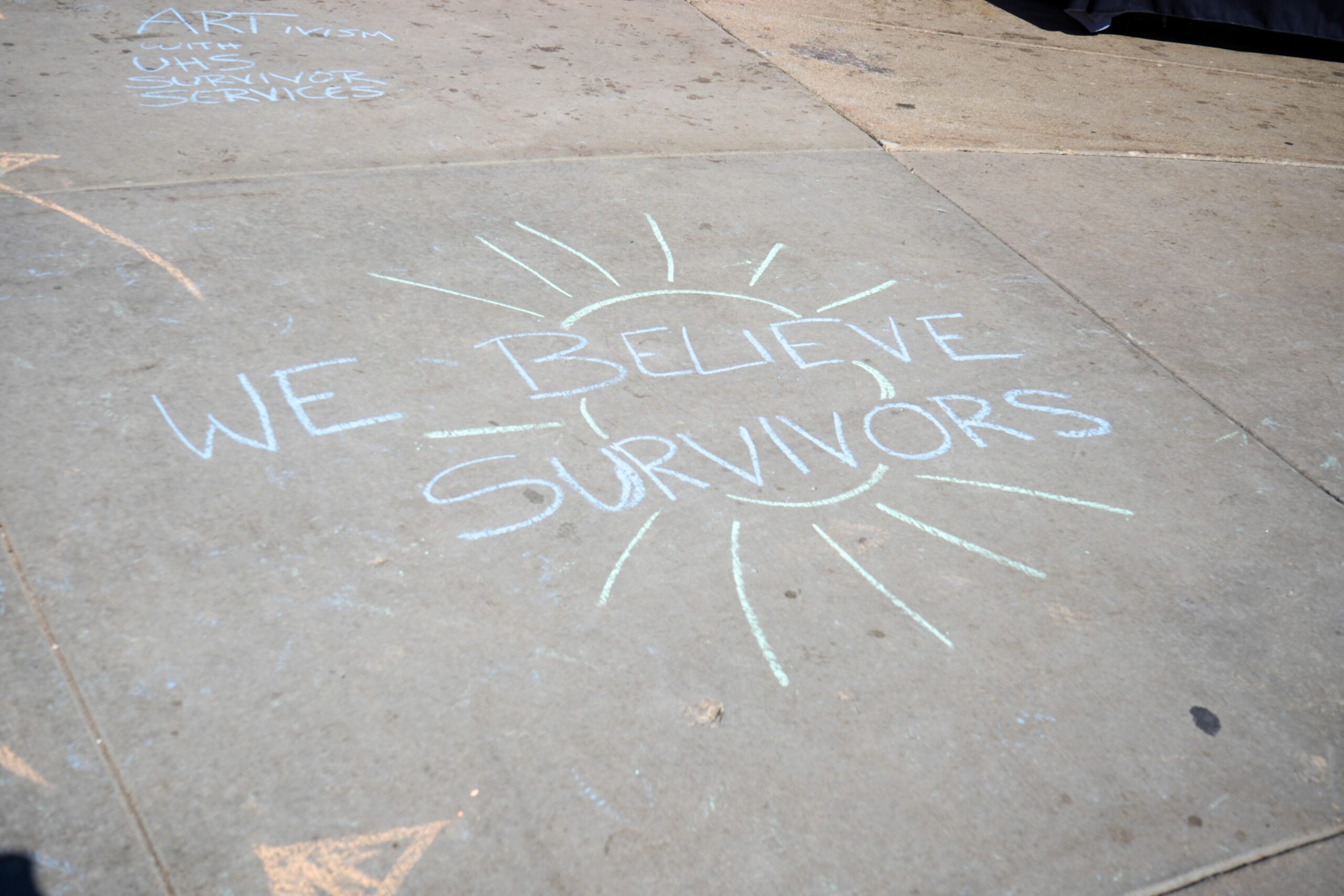 Sidewalk chalk reading "we believe survivors"